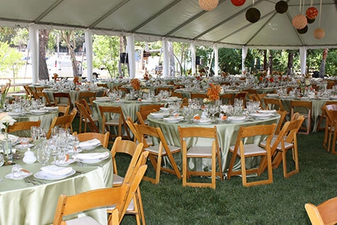Tables set with white table cloths in a banquet room with a view of a garden