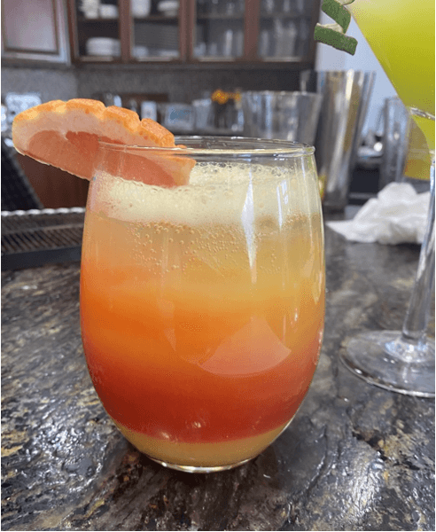 Tropical orange and yellow cocktail with a grapefruit garnish