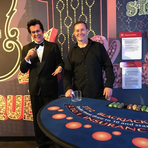 Elvis impersonator with a professional dealer in front of a blackjack table.